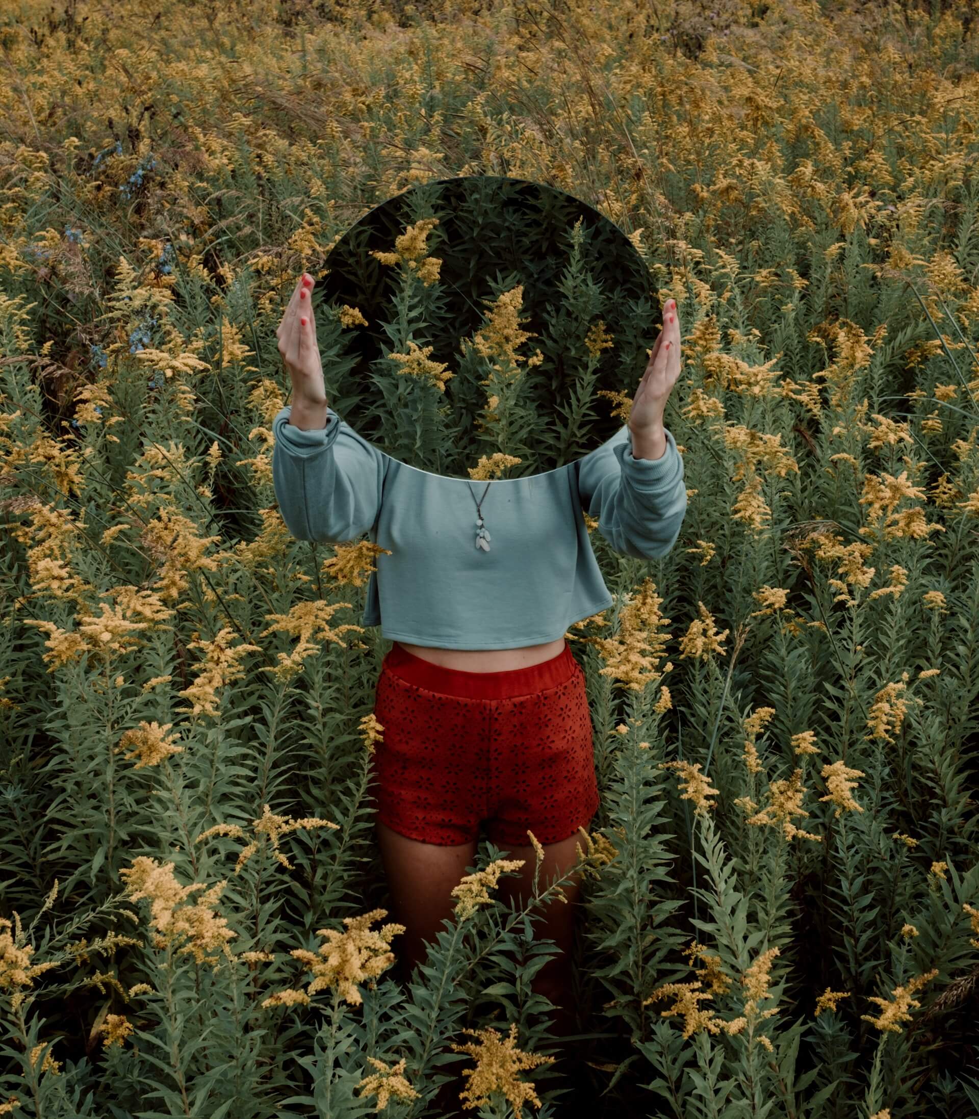 Kvinna i blomfält med en spegel.